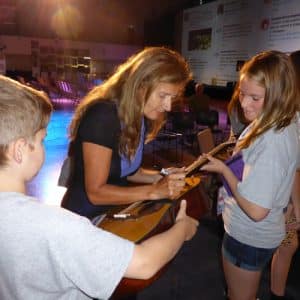 Dominique Dimey signe un autographe sur une guitare